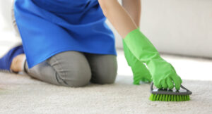 en kvinna rengör matta med borste
