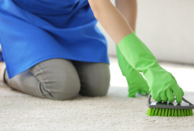 en kvinna rengör matta med borste